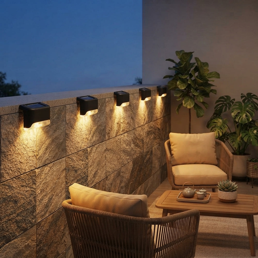 Solar LED deck lights glowing with warm amber light on a stone balcony wall at dusk.